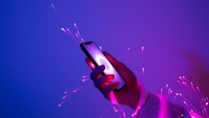 A hand holding a cellphone against purple sparkly background